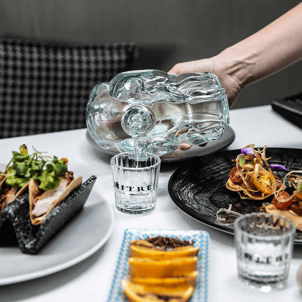 Mezcal Mitre Triple Agave servido para degustación junto a su icónica botella jaguar