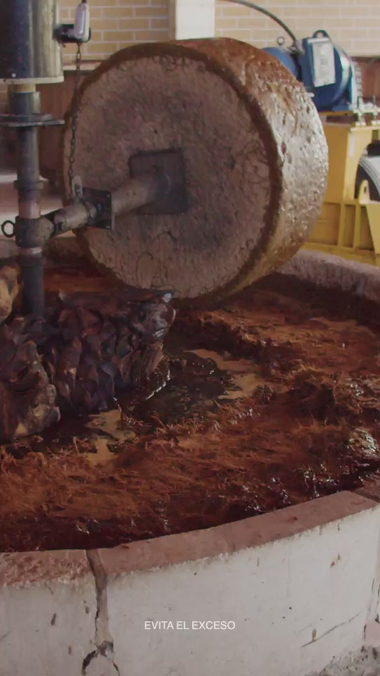 Molienda tradicional del agave con tahona de piedra en la producción artesanal de mezcal.